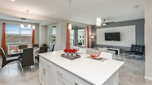 A modern kitchen with a large island, dining area, and a living space with a flat-screen TV. - Beautiful 2 Bdrm 2 BA Condo (Kissimmee)