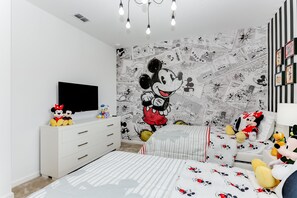 A child's bedroom with a large Mickey Mouse mural, a flat-screen TV, and Mickey-themed bedding. - 6056broa (Davenport)