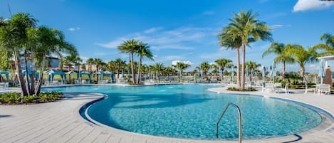 A circular pool with a metal ladder, surrounded by palm trees and lounge chairs on a tiled deck.