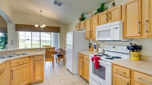 Une cuisine moderne avec des meubles en bois, une cuisinière blanche et une grande fenêtre.