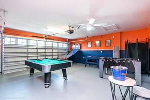 A recreational room with a pool table, foosball table, and a ping pong table.