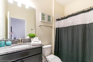 Ein Badezimmer mit einem weißen Waschbecken, einem Spiegel, einem Handtuchhalter und einer Toilette.