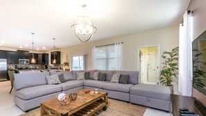 A modern living room with a sectional sofa, a wooden coffee table, and a kitchen in the background. - 6 Bedroom, 6 Bath Pool Home (Davenport)