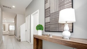 A modern hallway with a wooden console table, a potted plant, and a decorative wall piece. - 6052broa (Davenport)
