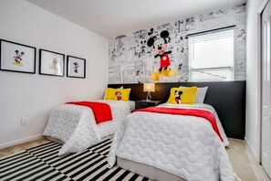 A room with two beds, a Mickey Mouse mural, and comic strip wallpaper. - 6052broa (Davenport)