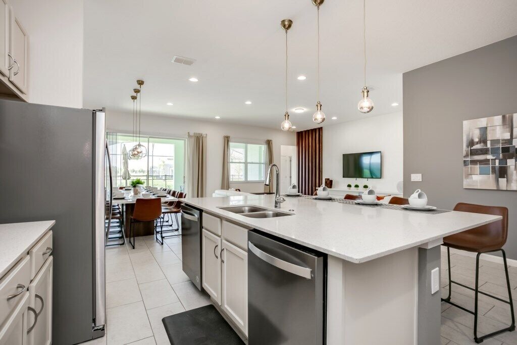 A modern kitchen with a central island, built-in appliances, and pendant lighting.