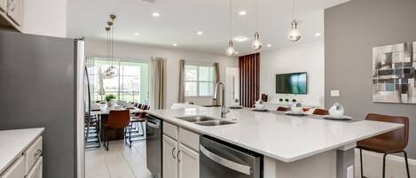 A modern kitchen with a central island, built-in appliances, and pendant lighting.