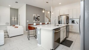 A modern kitchen with white cabinetry, stainless steel appliances, and pendant lighting. - 6052broa (Davenport)
