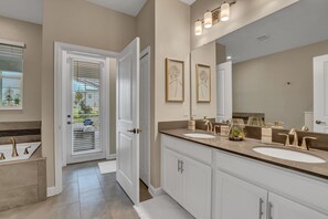 A modern bathroom with two sinks, a large mirror, and a door leading to a balcony.