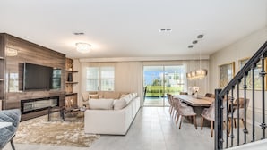 A spacious living room with a large TV, a fireplace, and a dining area with a view of the outdoors.