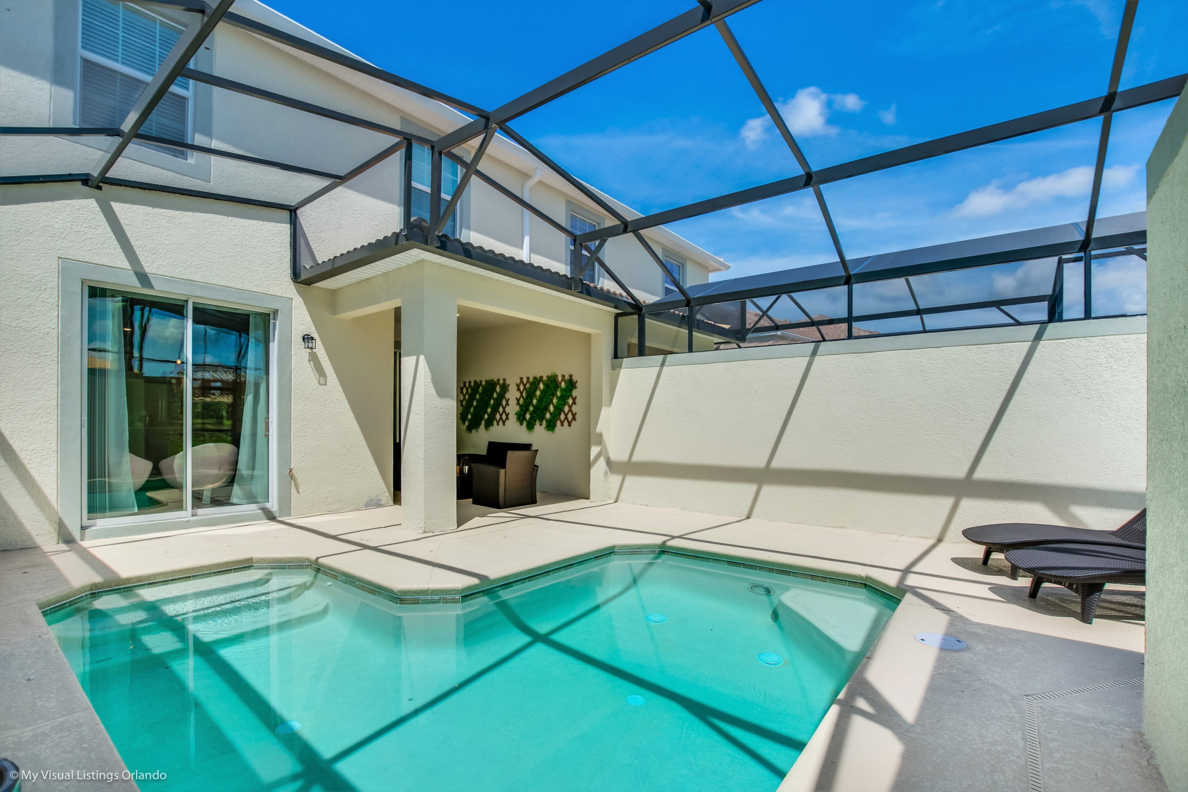 A modern house with a swimming pool, a covered patio, and a view of the sky.