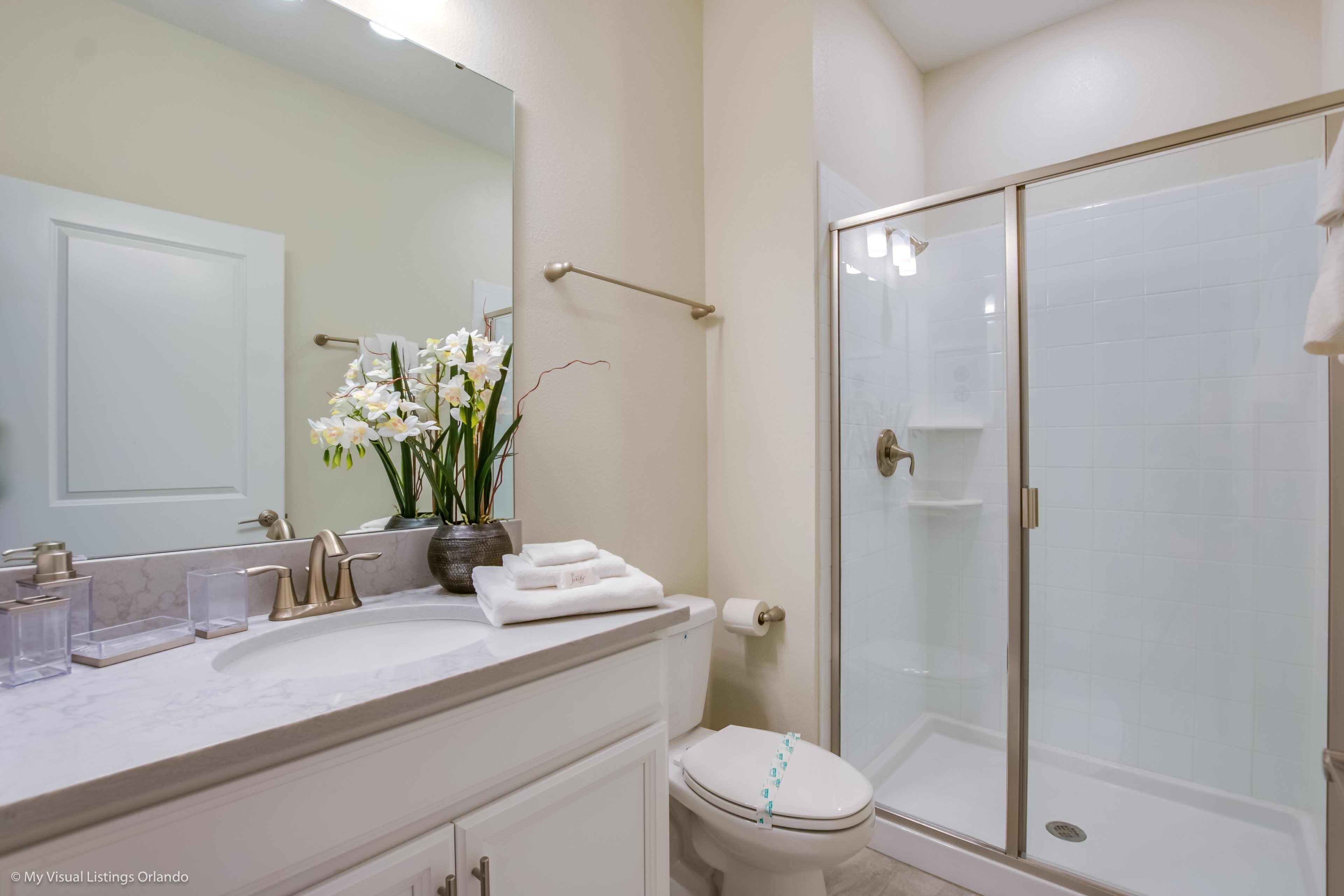 A bathroom with a white sink, a toilet, and a glass-enclosed shower.