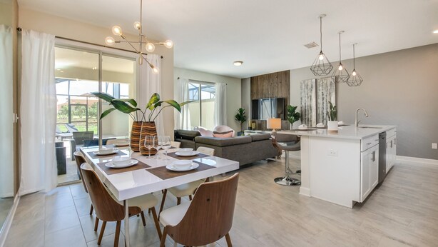 Eine moderne Küche mit einer zentralen Kochinsel, einem Essbereich mit Stühlen und Tisch sowie einer Wohnbereich mit Sofa und Fernseher.