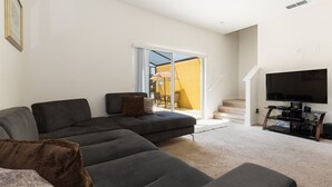 A modern living room with a sectional sofa, a flat-screen TV, and a dining area with a table and chairs. - Bella Vida 4568 IHR 1021 (Kissimmee)