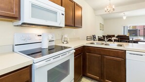 A modern kitchen with wooden cabinets, a built-in microwave, a stove, and a dishwasher. - Bella Vida 4568 IHR 1021 (Kissimmee)