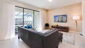 Un salon moderne avec un canapé gris, un meuble TV en bois et une grande fenêtre agrémentée de rideaux.