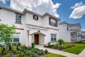 A two-story residential building with a white exterior, brown trim, and a tiled roof.