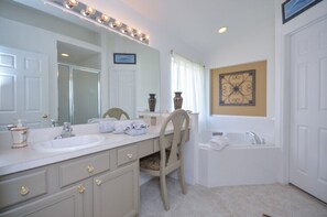 A bathroom with a double sink vanity, a chair, a bathtub, and a decorative wall piece. - 8524phd (Kissimmee)