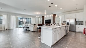 A spacious living area with a large island, a sofa, and a TV. - 9 Bed 6,5 Ba Villa Games, Pool & Spa (Kissimmee)