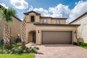 A residential house with a garage, a small attached structure, and a landscaped front yard with palm trees.