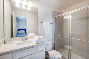 A modern bathroom with a large mirror, white sink, and a glass-enclosed shower.