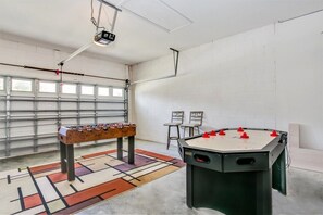 A room with two foosball tables, a projector, and a seating area with chairs. - 238north (Davenport)