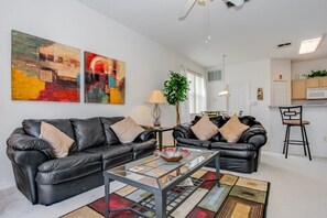 A modern living room with two black leather sofas, a glass coffee table, and abstract paintings on the wall. - 238north (Davenport)