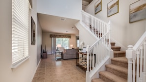 A spacious living area with a staircase, a sofa, and a coffee table. - 5bed 5Ba Villa Game Room Pool Spa (Kissimmee)