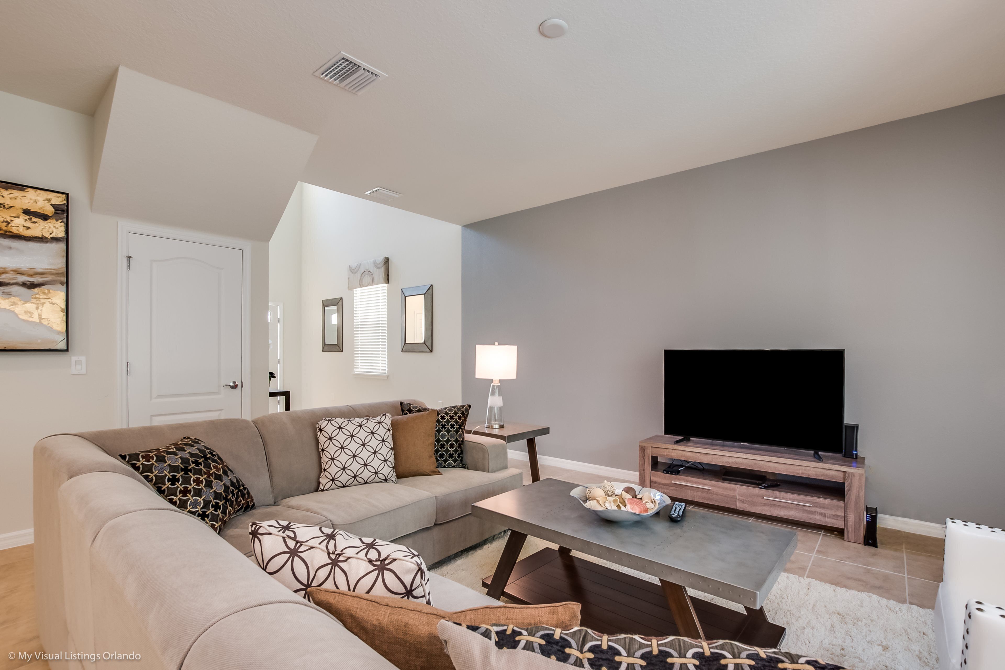 A modern living room with a sofa, coffee table, TV, and a lamp.