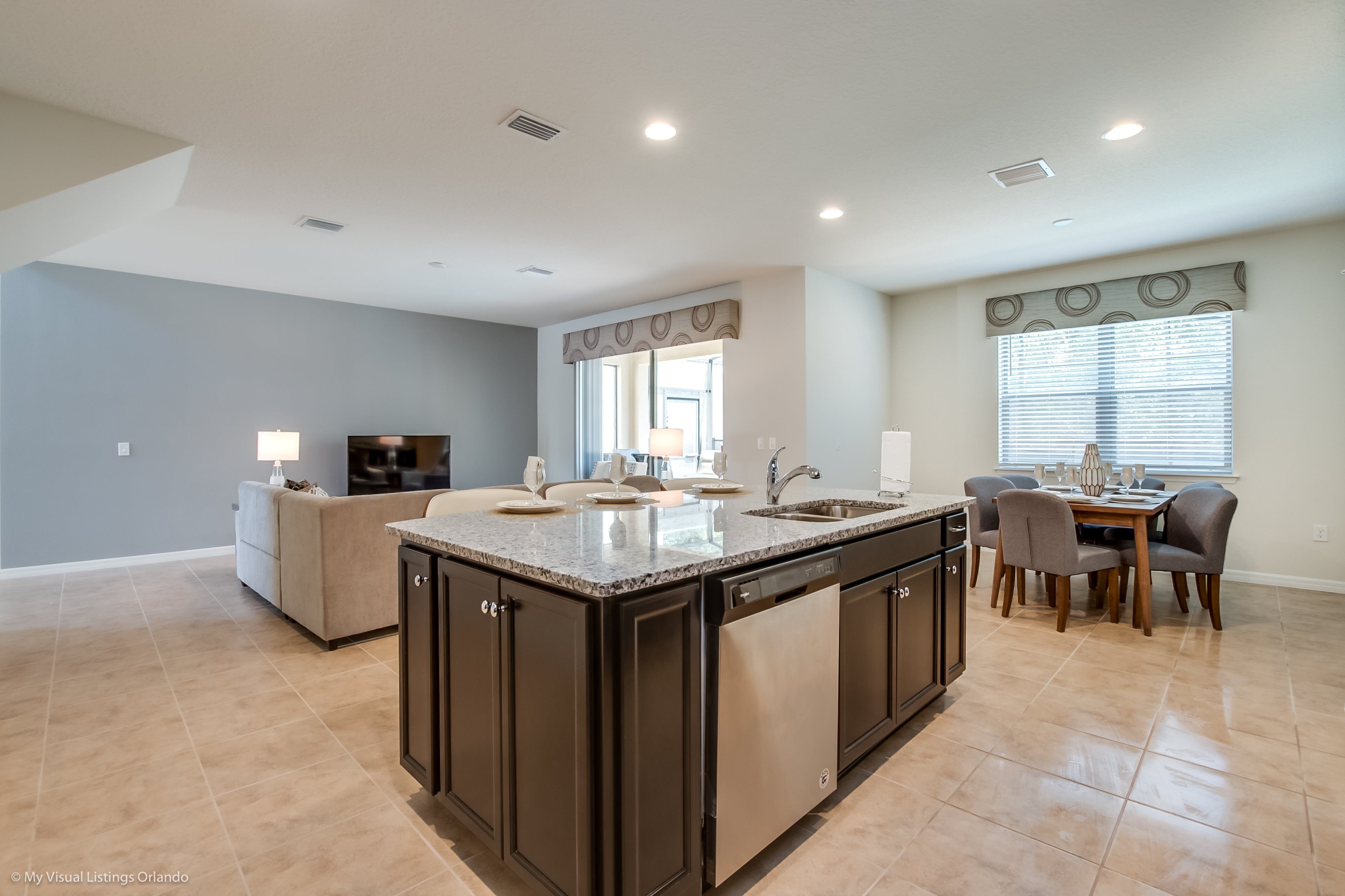 A spacious kitchen with a central island, dark cabinetry, and a dining area with a table and chairs.