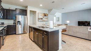 A modern kitchen with dark cabinets, stainless steel appliances, and a granite countertop. - 5bed 5Ba Villa Game Room Pool Spa (Kissimmee)
