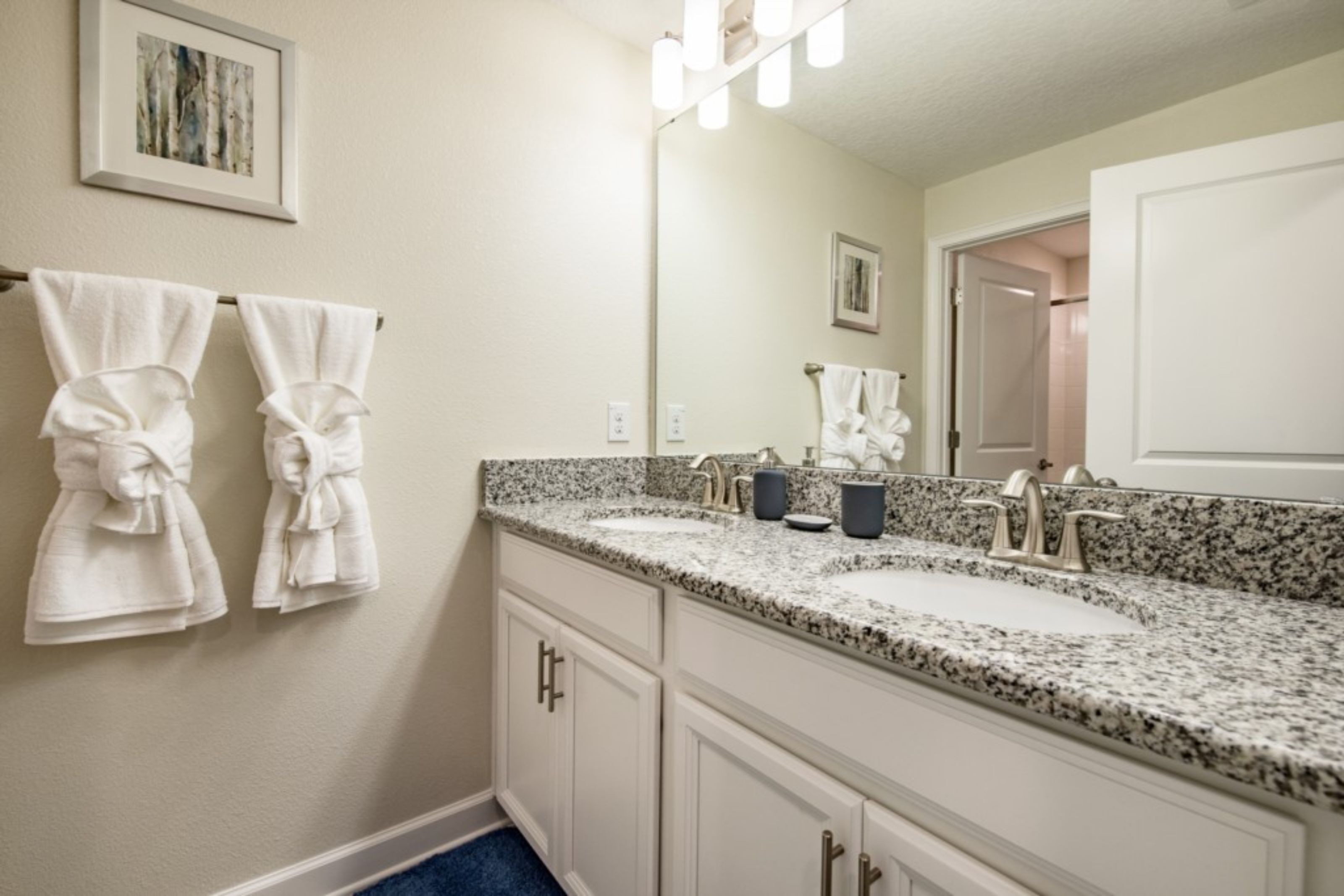 A bathroom with two sinks, a large mirror, and towels hanging on the wall.