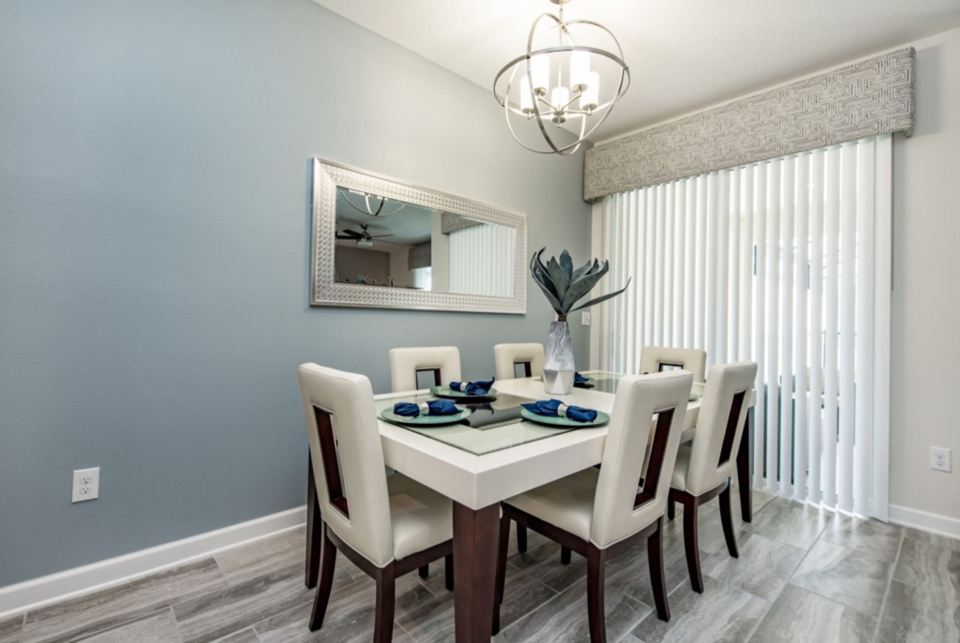A dining area with a white table, six chairs, and a chandelier.