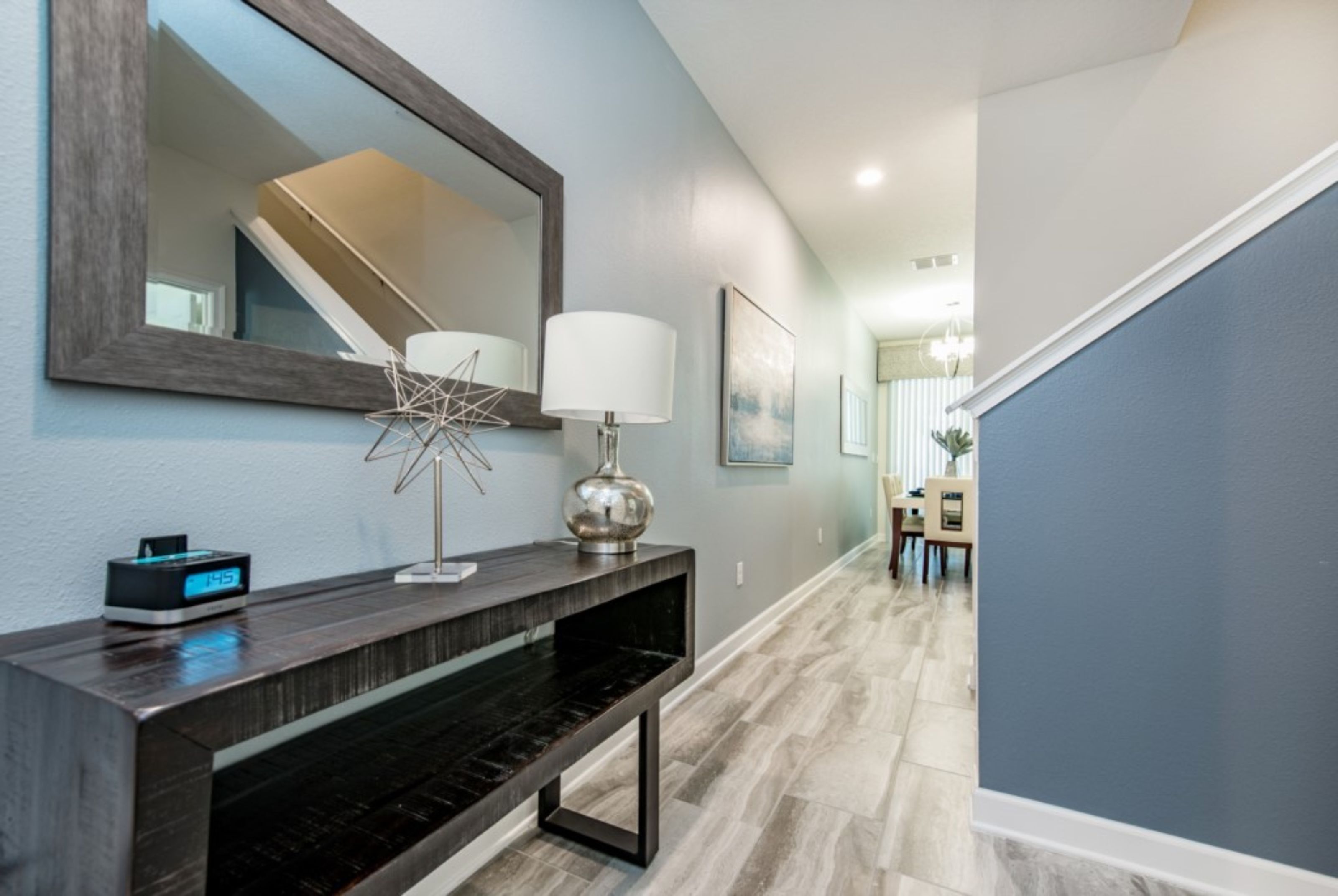 A modern hallway with a dark console table, a large mirror, and a wall-mounted lamp.