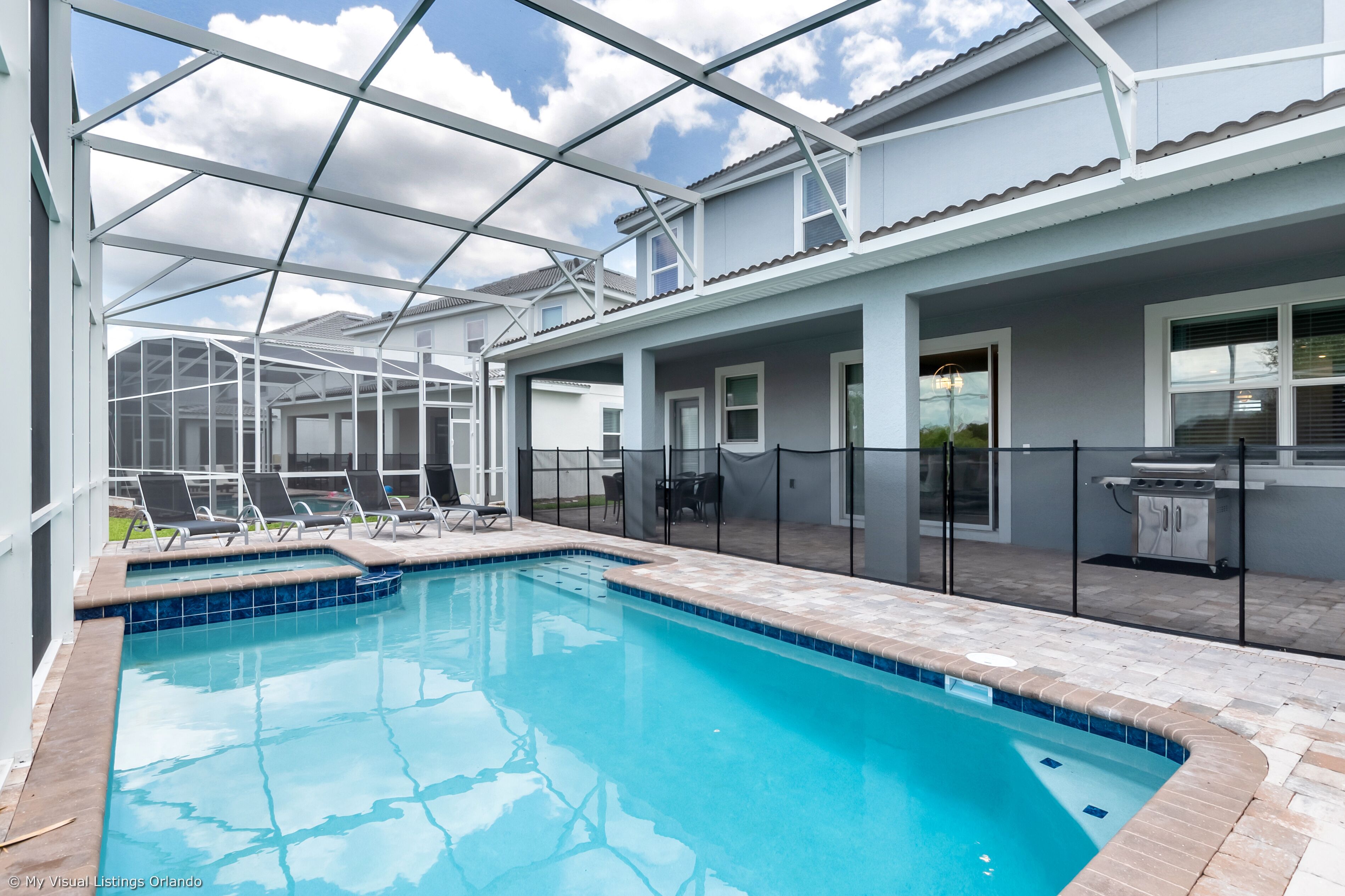 Une piscine dotée d’une structure en verre, d’un espace extérieur aménagé et d’un coin barbecue.