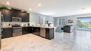 Una cocina moderna con armarios oscuros, electrodomésticos de acero inoxidable y una isla grande.