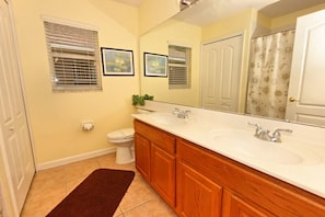A bathroom with a double sink vanity, wooden cabinets, a large mirror, and a toilet. - 538 Brig (Davenport)
