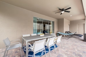 A patio with a table and chairs, a ceiling fan, and a view through a glass door. - 1607lima (Kissimmee)
