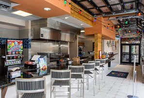 A restaurant with a bar area, seating, and a kitchen in the background. - 4582terra (Davenport)
