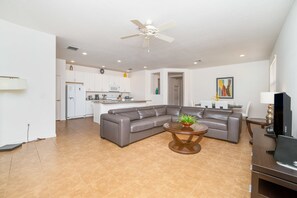 A modern living room with a sectional sofa, a round coffee table, and a flat-screen TV.