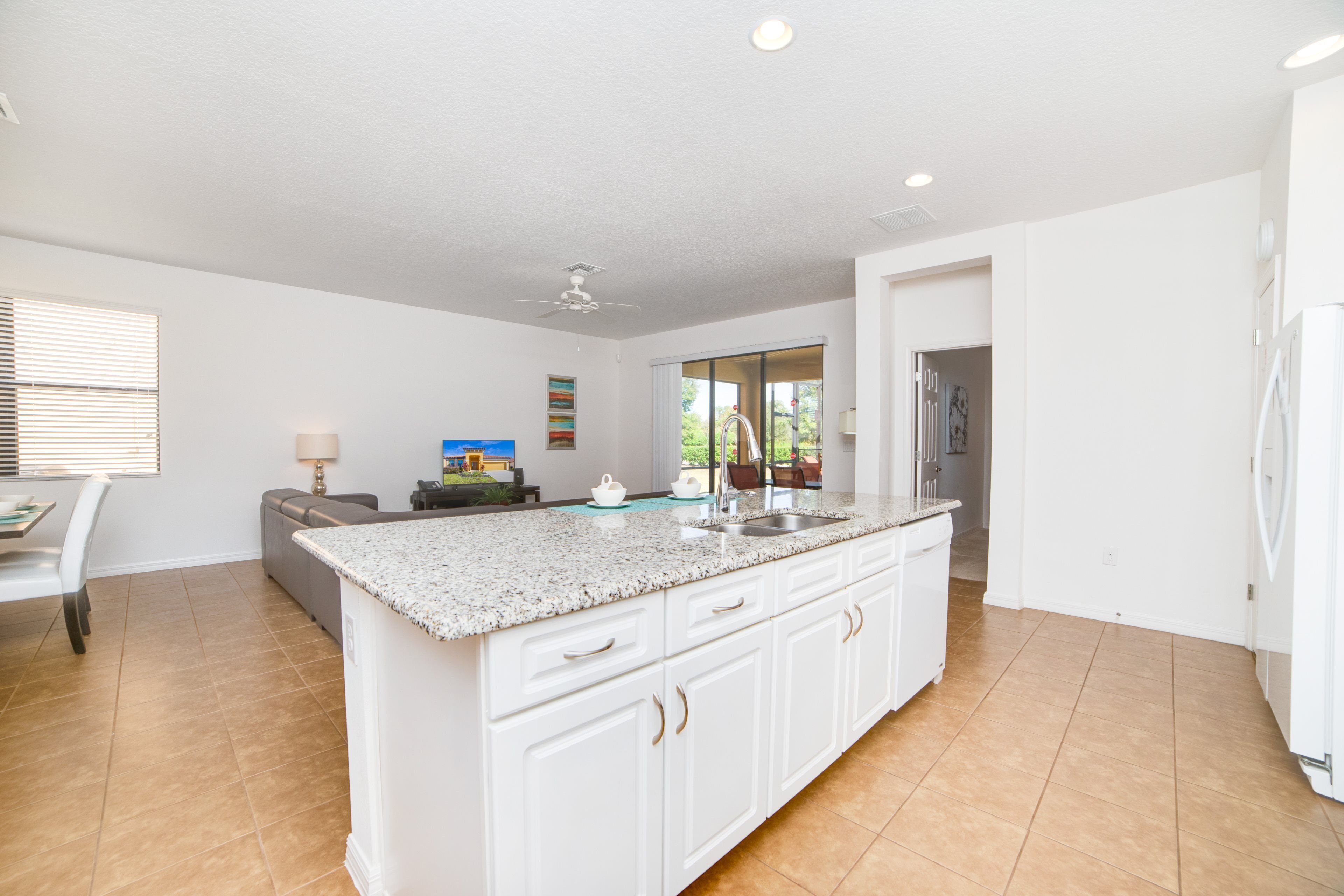 A spacious kitchen with a central island, white cabinetry, and a large window providing natural light.