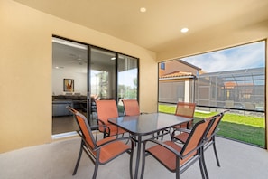A modern patio with a glass door leading to a living area, a glass-enclosed outdoor kitchen, and a view of a residential area. - 2509rose (Davenport)