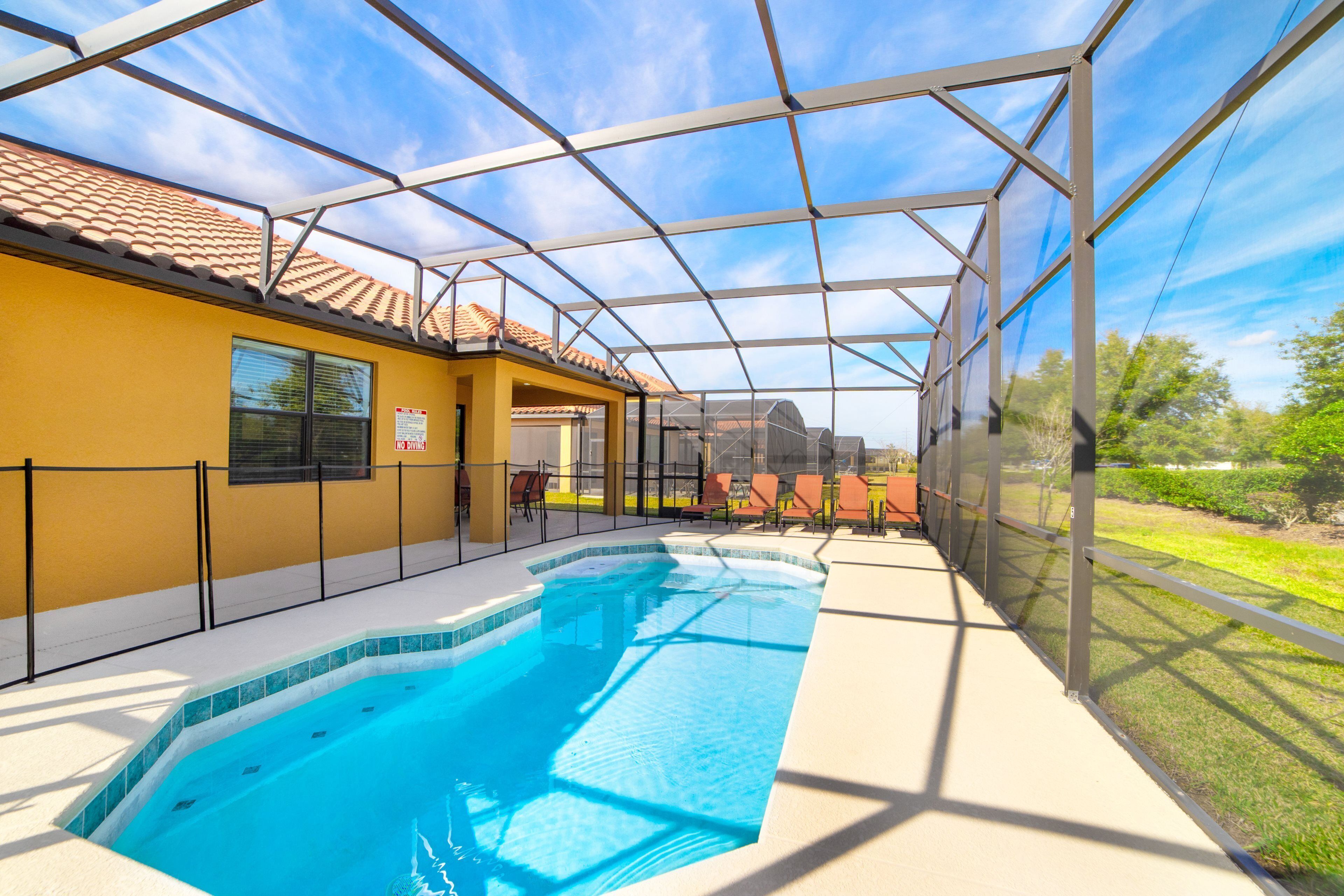 A covered outdoor swimming pool with a yellow building and a clear sky.