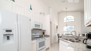 A modern kitchen with white cabinetry, a built-in oven, microwave, and refrigerator. - 2360victoria (Davenport)