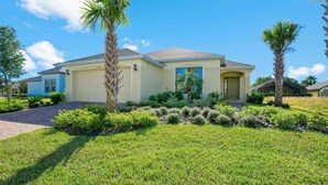 A single-story house with a garage, surrounded by well-maintained grass and palm trees. - 2360victoria (Davenport)