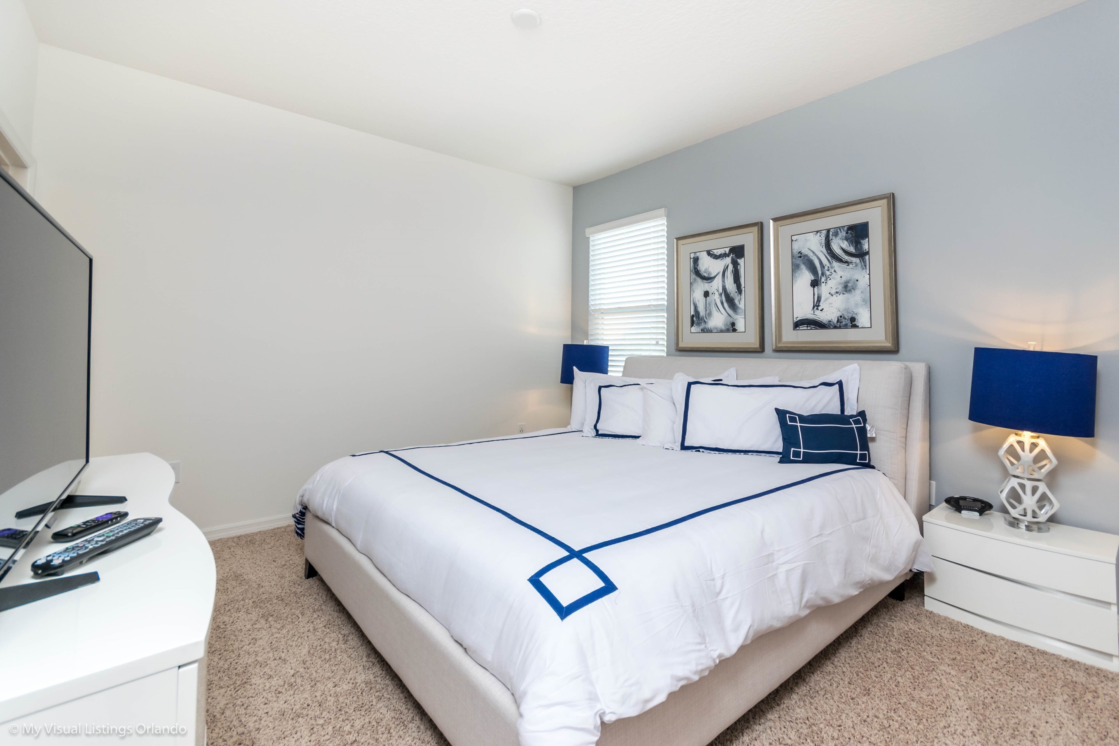 A bedroom with a large bed, a bedside table, a desk, and two wall-mounted lamps.