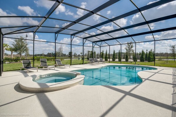Una piscina exterior techada con sillones de descanso, un jacuzzi y vistas del paisaje circundante.