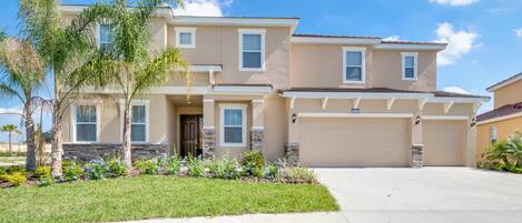 A two-story house with a garage, a front porch, and a well-maintained lawn.