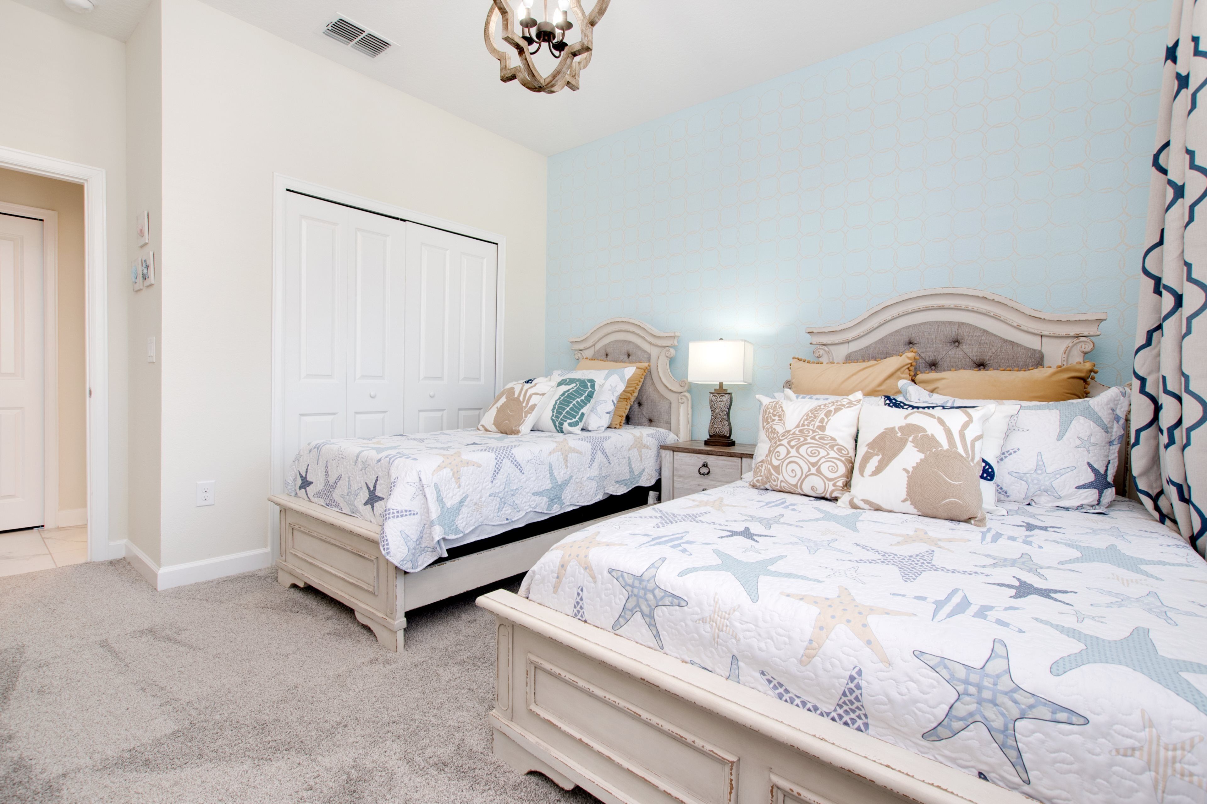Quarto com duas camas, mesa de cabeceira e cômoda.