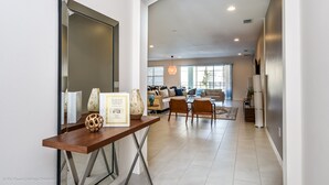 Amplio espacio habitable con diseño moderno, que incluye una consola de madera, un espejo grande y una zona de estar con sofás y sillones.